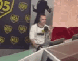 a man is sitting at a desk in front of a microphone .