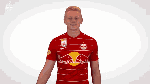 a man wearing a red and white striped shirt with a red bull on it salutes