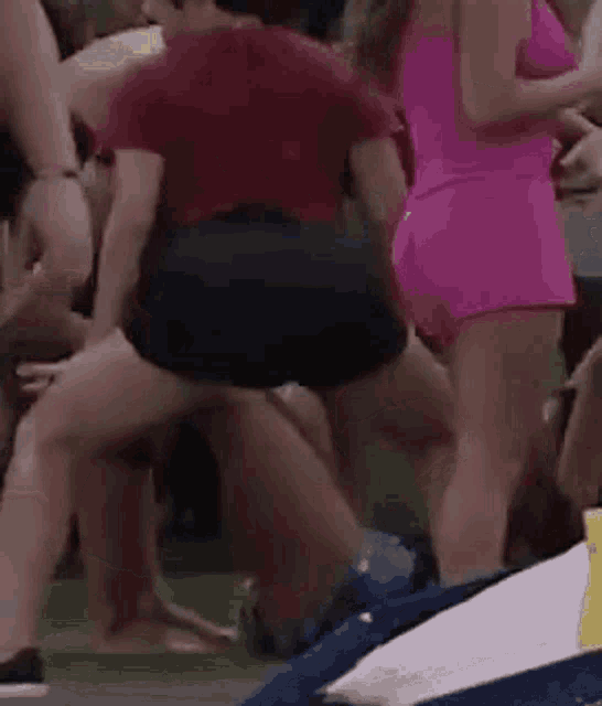 a group of people are standing around a woman in a pink dress who is squatting down .