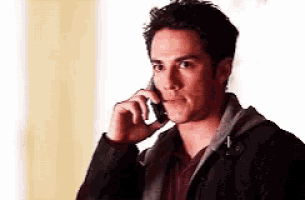 a man in a black jacket is talking on his cell phone
