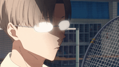 a man wearing glasses holds a tennis racquet