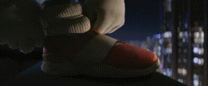 a close up of a person holding a red object in front of a window at night .