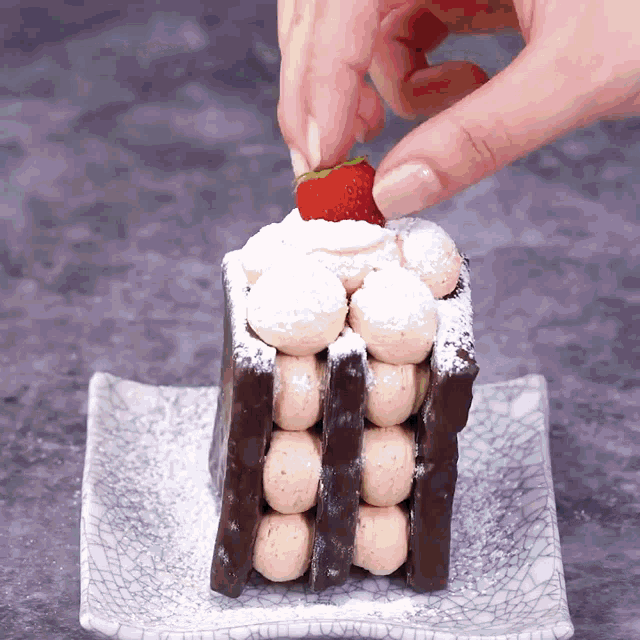 a person putting a strawberry on top of a cake