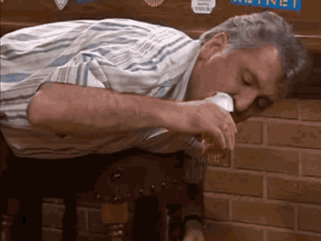 a man is drinking a beer while sitting at a bar
