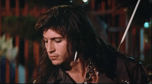a man with long hair and a scarf around his neck is looking down