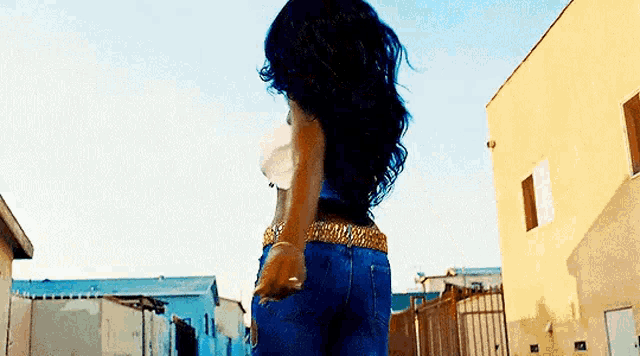 a woman in a blue dress is standing in front of a building in a city .