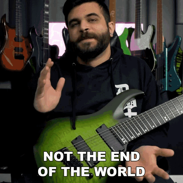 a man holding a green guitar with the words not the end of the world