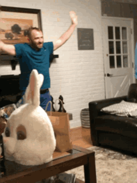 a man in a blue shirt stands next to a stuffed bunny