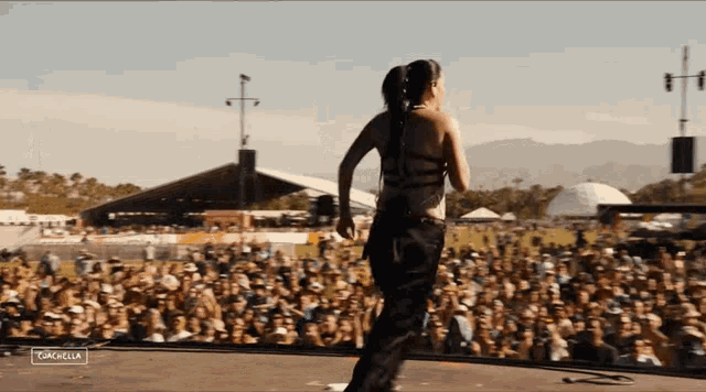 a woman stands on a stage in front of a crowd and the word coachella is on the bottom right