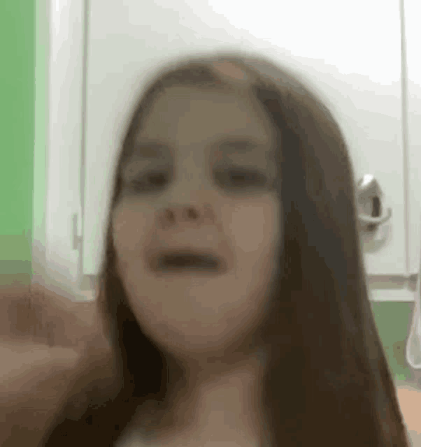 a little girl with long hair is making a funny face in a bathroom .