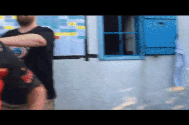 a man in a black shirt is standing in front of a blue box