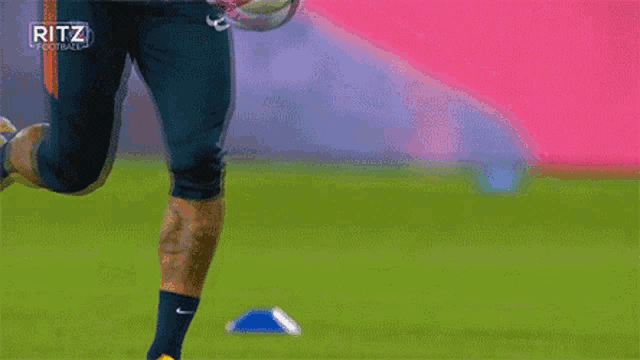 a soccer player is kicking a soccer ball on a field with ritz football written on the bottom