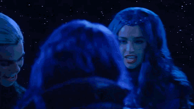 a woman with blue hair is blowing a kiss to another woman