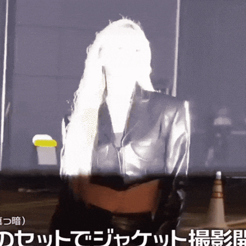 a woman in a leather jacket is standing in front of a sign that says ' a ' on it