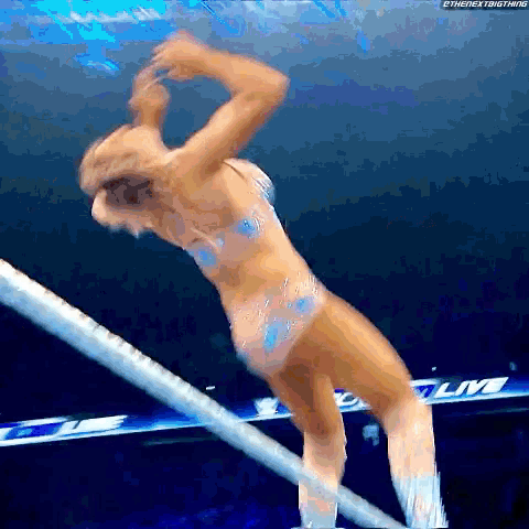 a woman in a bikini is standing on a rope in a ring .