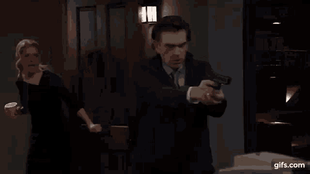 a man in a suit and tie is standing in a dark room with a light on the wall .