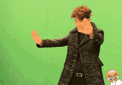 a man in a leather jacket is dancing in front of a green screen with chinese writing on it