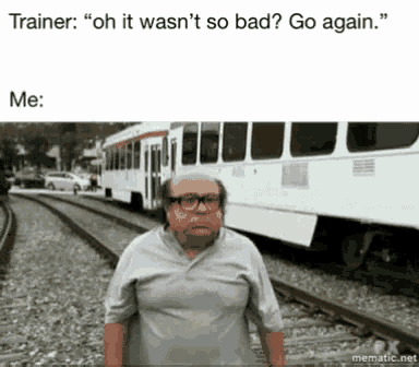 a man with glasses is standing on train tracks next to a train