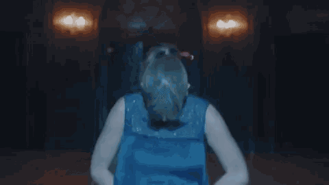 a woman in a blue dress is standing in a dark room with lights on .