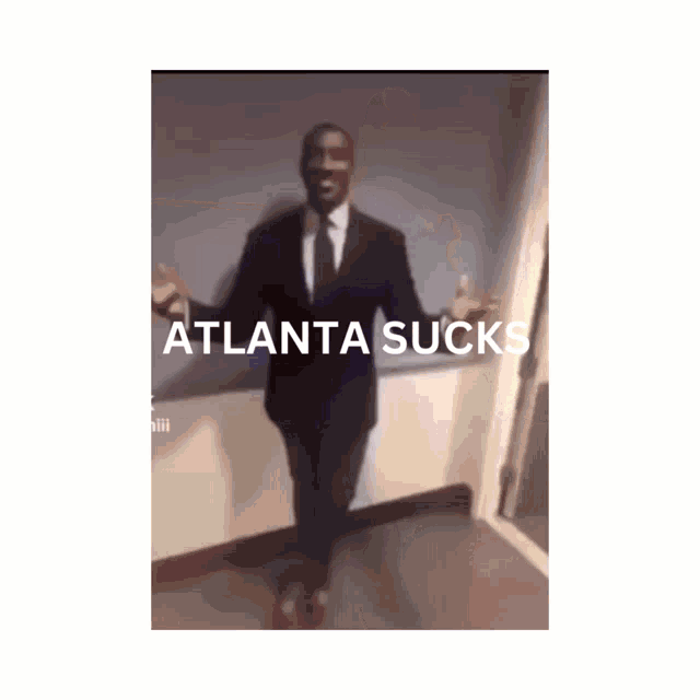 a man in a suit and tie stands in a hallway with atlanta sucks written on the bottom