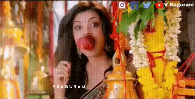 a woman is eating a red apple in front of flowers and a sign that says vraguram