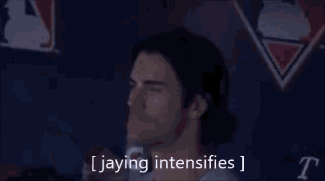 a man is sitting in a stadium with his eyes closed and the words jaying intensifies written on the screen .