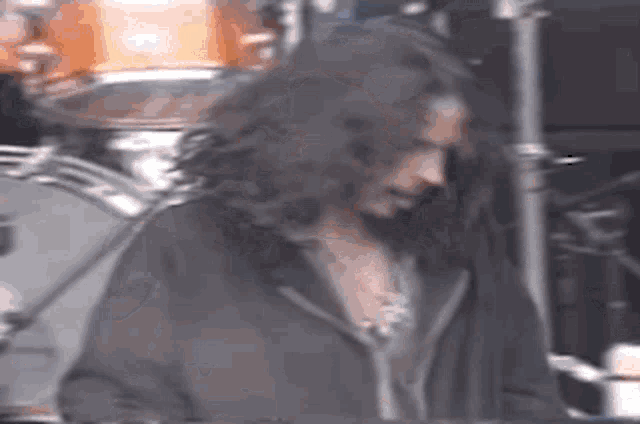 a man with long hair and a beard is playing a drum set on a stage .