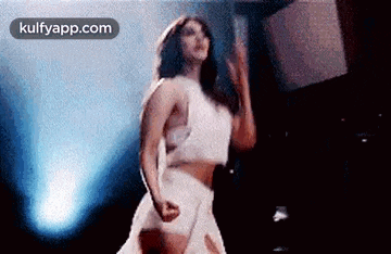 a woman in a white dress is dancing on a stage in front of a blue light .