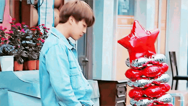 a man standing next to a stack of red balloons