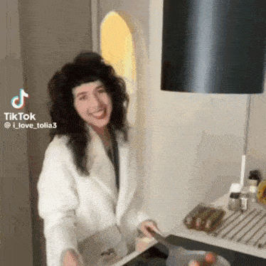 a woman in a white coat is cooking on a stove .