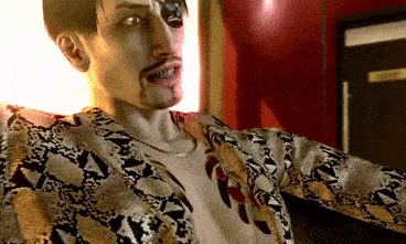 a man wearing a snake print shirt is standing in front of a red wall