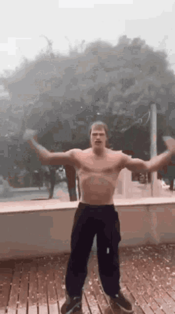 a shirtless man is dancing in the rain