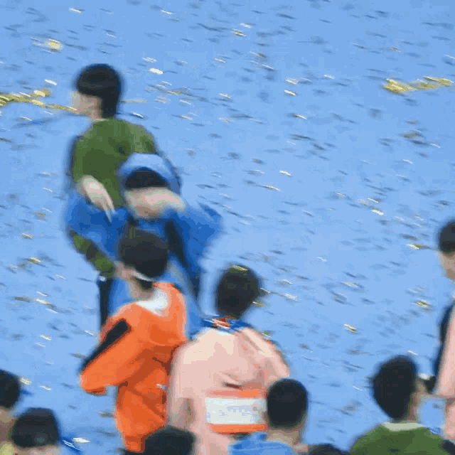 a group of people are standing on a blue surface with confetti falling