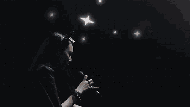 a woman singing into a microphone with her arms in the air