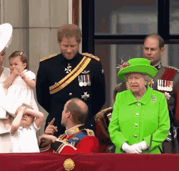 the queen is wearing a green hat while standing next to a man in a red uniform .