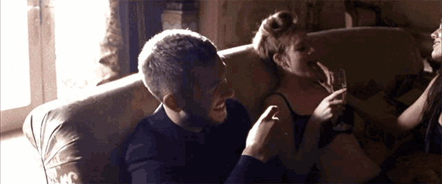 a man and woman are sitting on a couch and the man is laughing
