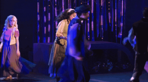a group of people are dancing on a stage in a dark room .