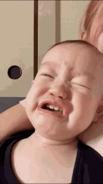 a baby is crying with his eyes closed and his teeth showing