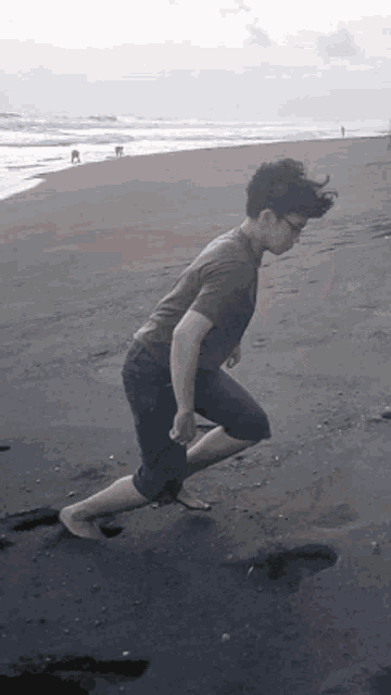 a man in a green shirt is running barefoot on the beach
