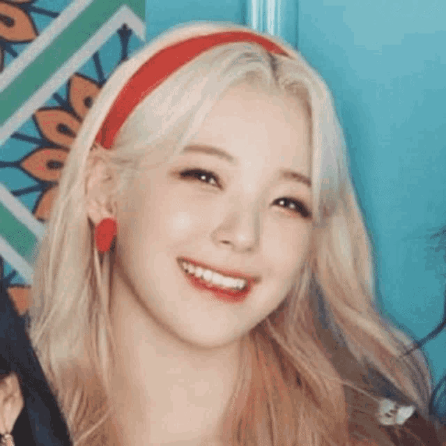 a close up of a woman with blonde hair wearing a red headband and earrings .
