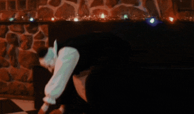 a clown in a white and black outfit is sitting on a bench