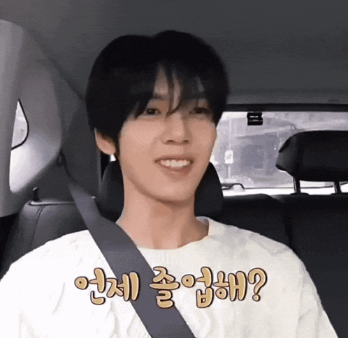 a man wearing a white shirt and a seat belt is smiling