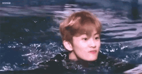 a young boy is swimming in a pool of water .