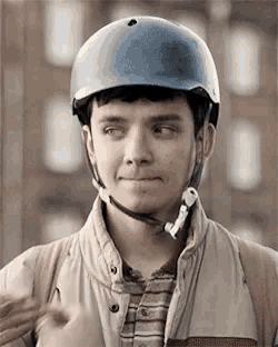 a young man wearing a helmet and a jacket looks at the camera