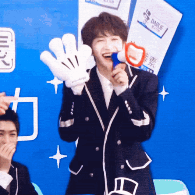 a man in a suit is holding a microphone and a pair of gloves