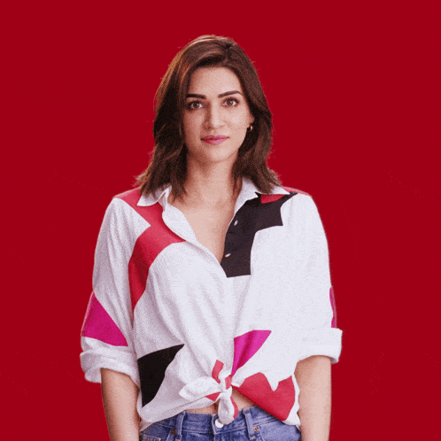 a woman wearing a colorful shirt is clapping her hands in front of a red background
