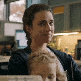 a woman holds a baby in her arms and looks at the camera