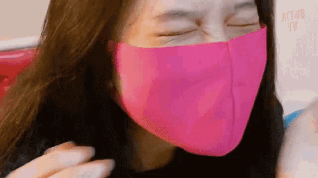 a woman wearing a pink face mask making a funny face