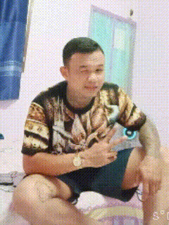 a man is sitting on a bed wearing a shirt with a leopard print and shorts .