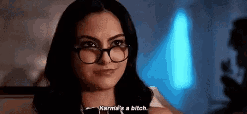 a woman wearing glasses is talking to someone and says `` karma 's a bitch '' .